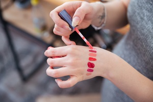 woman makeup artist testing private label lip gloss different colors on her hand